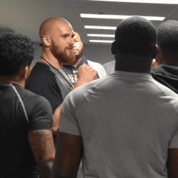 Strength coach speaking with athletes in the weight room